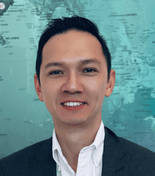 Franchise development professional at United Franchise Group standing in front of a world map, promoting franchise opportunities and global business expansion.