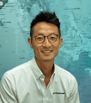 Franchise professional smiling in front of a world map, representing United Franchise Group's global franchise opportunities and business support services.
