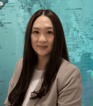 Professional woman in front of a world map representing global franchise opportunities with United Franchise Group.