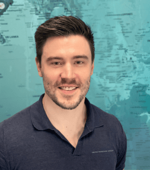 Highly skilled male franchise owner standing in front of a world map, representing global franchise opportunities and business growth with United Franchise Group.